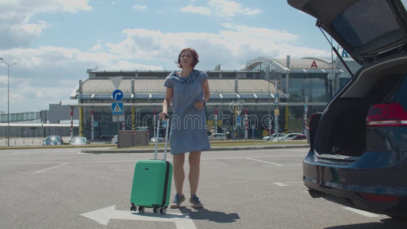 Joven mujer feliz bailando sola con maleta cerca del edificio del aeropuerto. mujer turista está feliz de viajar. dama emocionada