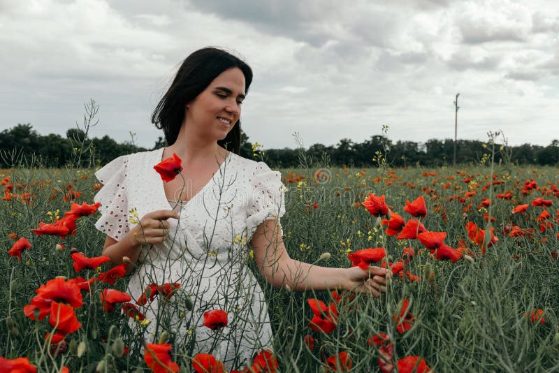 Joven mujer feliz caminando en un floreciente campo de amapola fotografía de archivo
