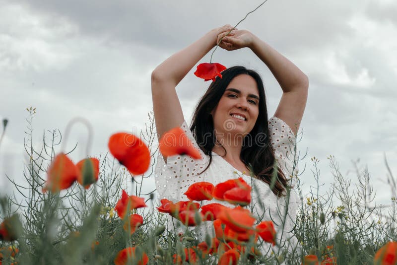 Joven mujer feliz caminando en un floreciente campo de amapola imagenes de archivo