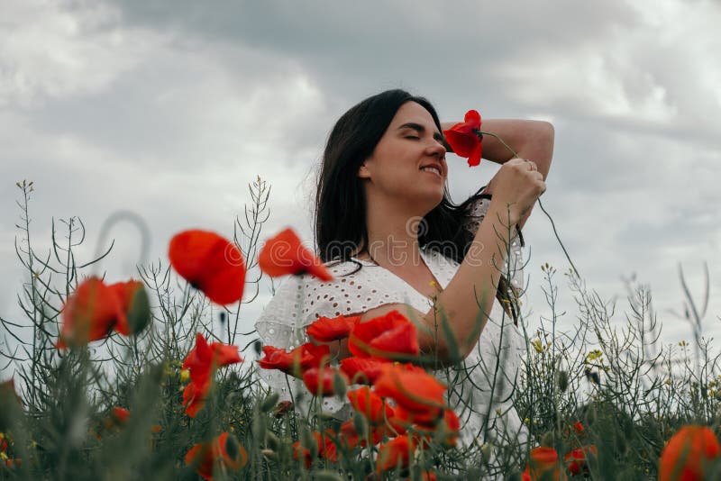 Joven mujer feliz caminando en un floreciente campo de amapola foto de archivo