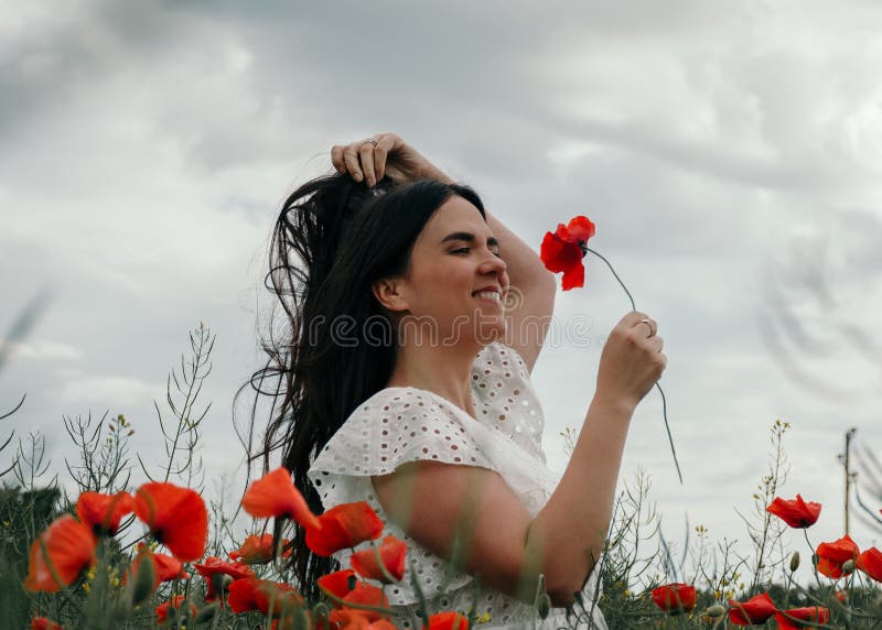 Joven mujer feliz caminando en un floreciente campo de amapola imagen de archivo