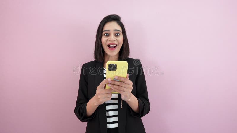 Joven mujer feliz del sur de Asia mirando un celular con una expresión sorprendida metrajes
