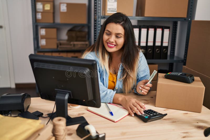 Joven mujer hermosa más grande comercio de comercio electrónico contando dólares usando calculadora en la oficina