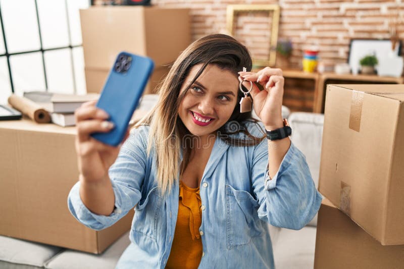 Joven mujer hermosa más grande con videollamada sosteniendo la llave en su nuevo hogar fotos de archivo