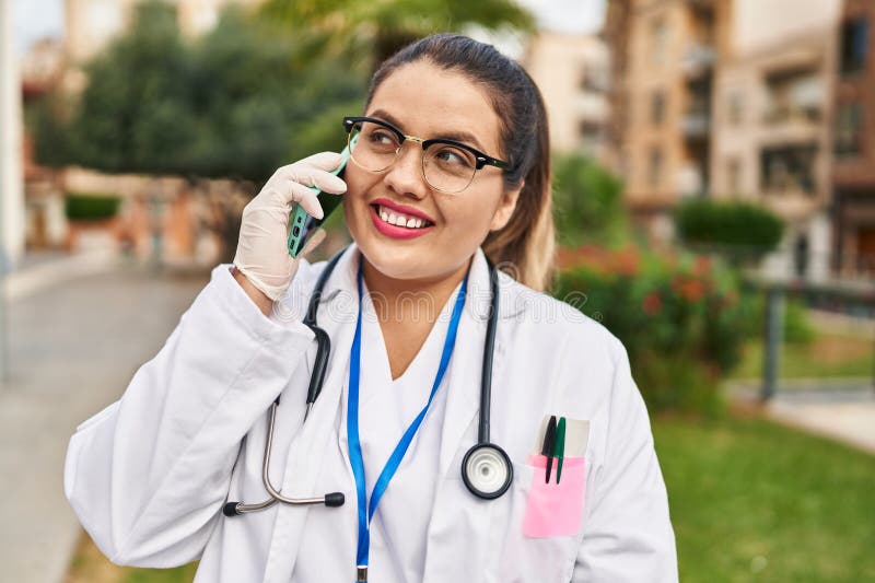 Joven mujer hermosa más grande doctor sonriente confiado hablando en el smartphone del parque imágenes de archivo libres de regalías