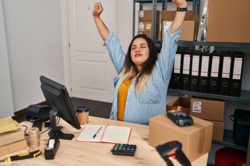 Joven mujer hermosa más grande mujer ecommerce empresaria estirando los brazos en la oficina imagen de archivo