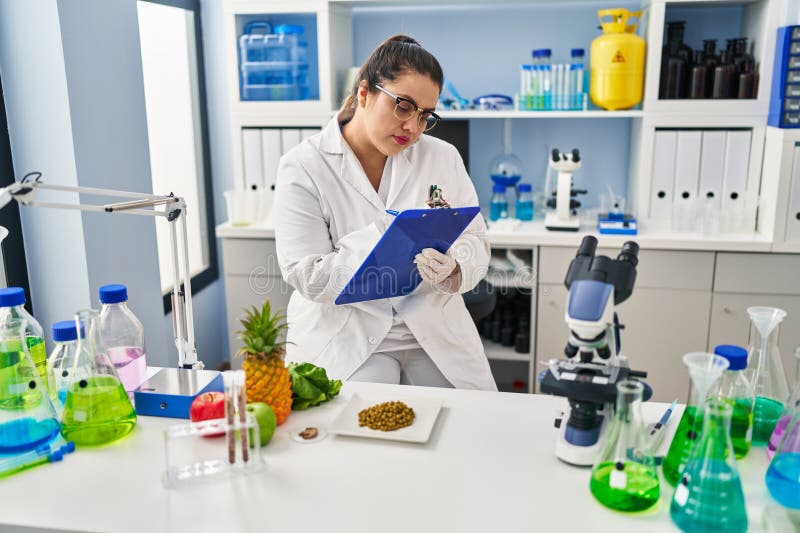 Joven mujer hermosa más grande que escribe un informe de trabajo en la farmacia imagen de archivo libre de regalías