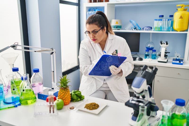 Joven mujer hermosa más grande que escribe un informe de trabajo en la farmacia fotos de archivo
