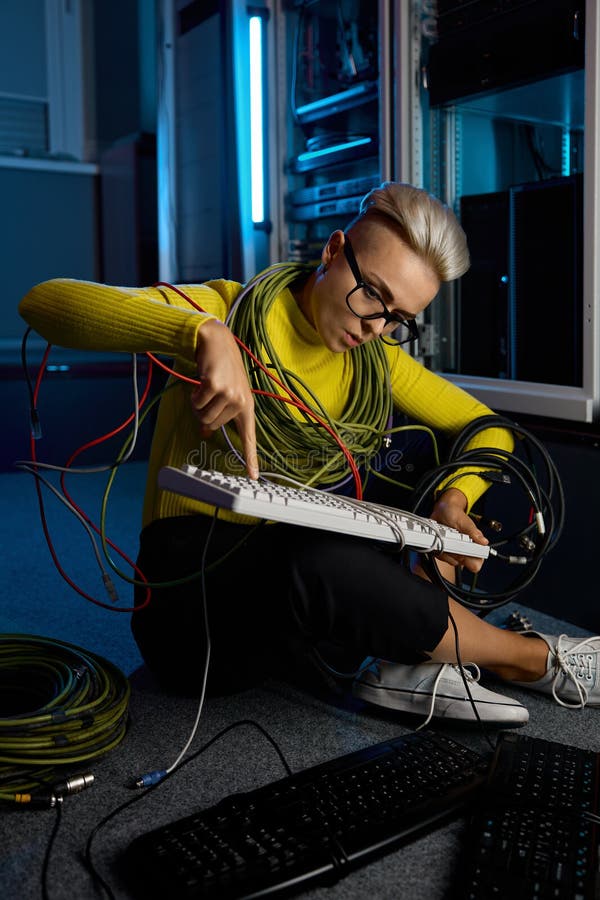 Joven mujer técnica de tecnología informática envuelta en el teclado de reparación de alambre fotografía de archivo