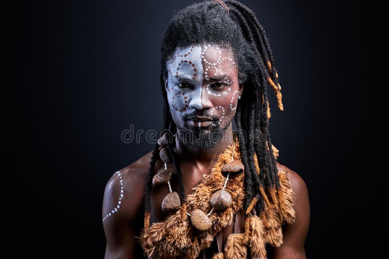 Joven negro con chamán aborigen maquillaje con confianza mirando a cámara imágenes de archivo libres de regalías