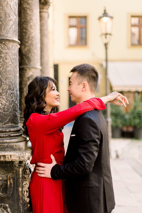 Joven pareja china en el amor abrazándose en la calle de la ciudad vieja, vacaciones de verano en Europa, viajes, diversión, fel foto de archivo Joven pareja china en el amor abrazándose en la calle de la ciudad vieja, vacaciones de verano en Europa, viajes, diversión, fel foto de archivo