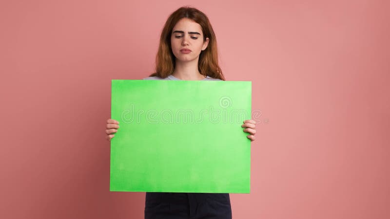 Joven preocupada y molesta sosteniendo un panel verde almacen de video