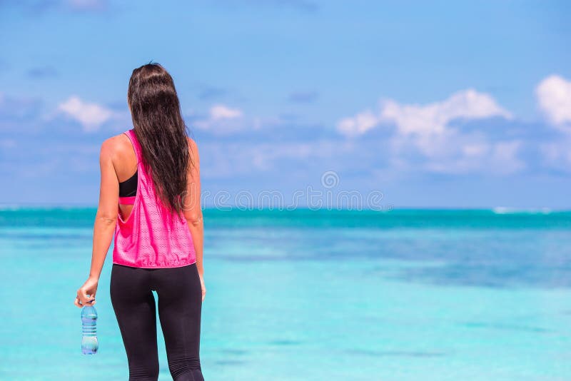 Joven que hace ejercicios en una playa tropical blanca en su ropa deportiva fotos de archivo libres de regalías Joven que hace ejercicios en una playa tropical blanca en su ropa deportiva fotos de archivo libres de regalías