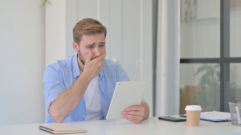 Joven reaccionando a la pérdida en el comprimido. Joven creativo reaccionando a la pérdida en tablet
