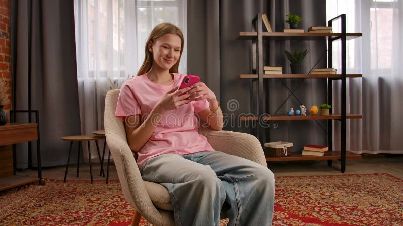 Joven relajándose en una habitación acogedora mientras usa Smartphone metrajes