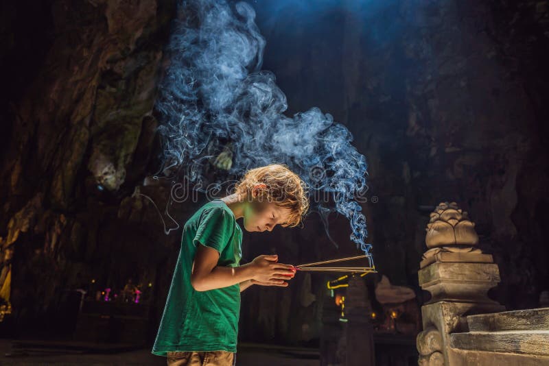 Joven rezando en un templo budista sosteniendo la cueva de incense huyen khong con santuarios de las montañas de mármol vietnam