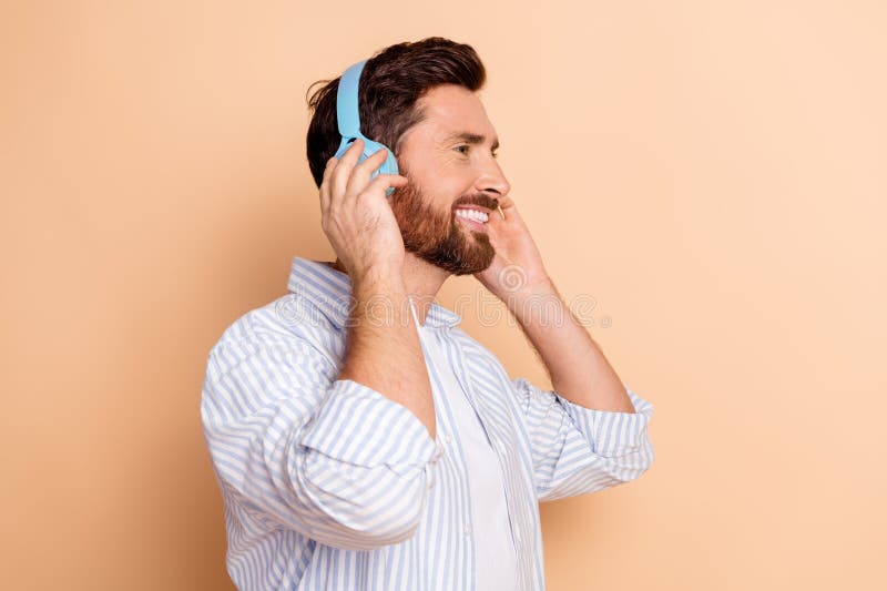 Joven sonriente disfrutando de la música con auriculares en un ambiente relajado e informal con un agradable entorno foto de archivo