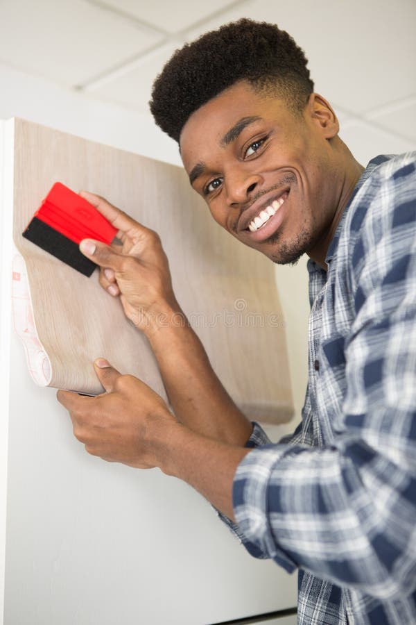 young worker making repair in room wallpapering on wall installation. young worker making repair in room wallpapering on wall installation