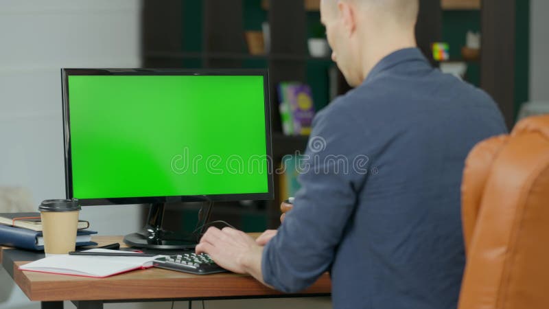 Joven trabajando en computadora de escritorio con pantalla verde se burla en oficina moderna almacen de metraje de vídeo
