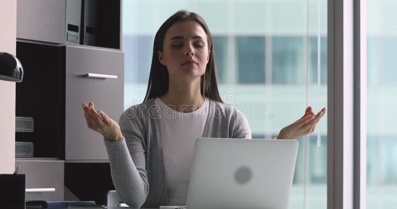 Joven tranquila y consciente medita en el trabajo con los ojos cerrados