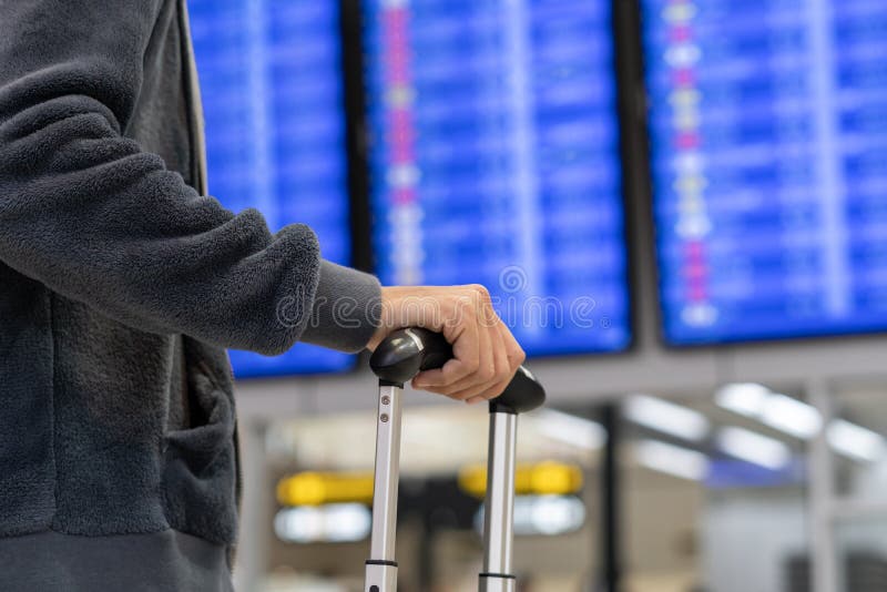 Joven viajera con equipaje mirando el tablero de información de vuelo en el aeropuerto foto de archivo Joven viajera con equipaje mirando el tablero de información de vuelo en el aeropuerto foto de archivo