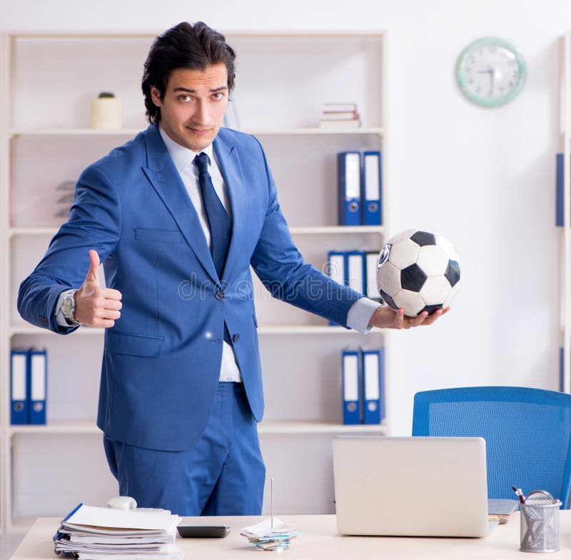 Joven y apuesto hombre de negocios con fútbol en la oficina imágenes de archivo libres de regalías