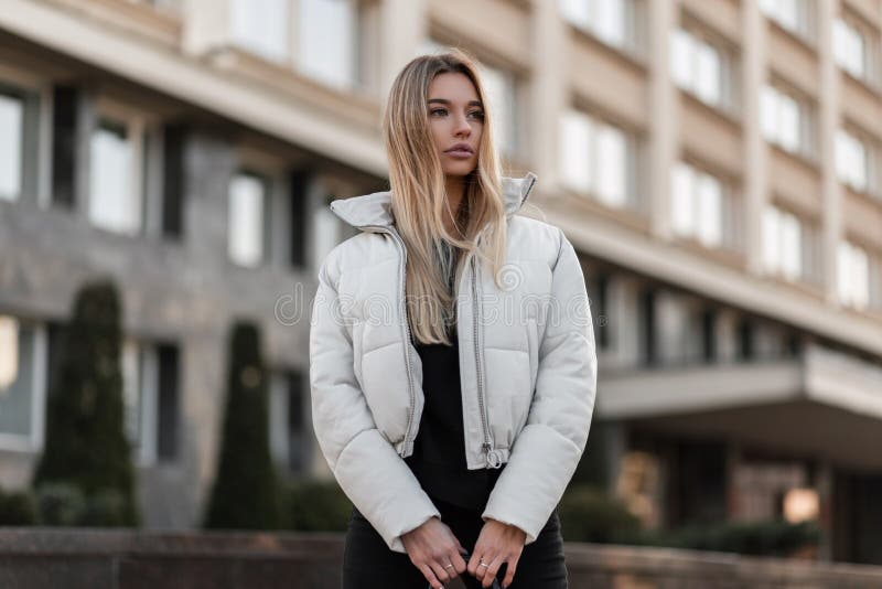 Joven Y Elegante Modelo De Una Hermosa Mujer Con El Pelo Largo Rubio En Una  Elegante Chaqueta Blanca Se Pone En El Exterior En Un Imagen de archivo -  Imagen de gente