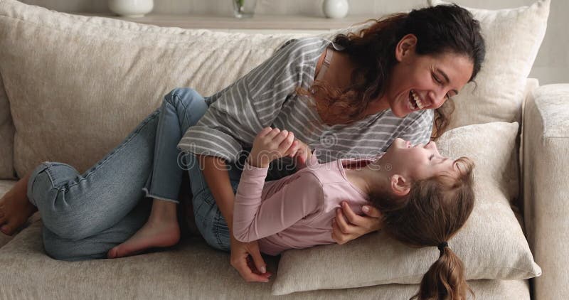 Joven y feliz madre hispana haciendo cosquillas, pequeña hija riéndose. metrajes