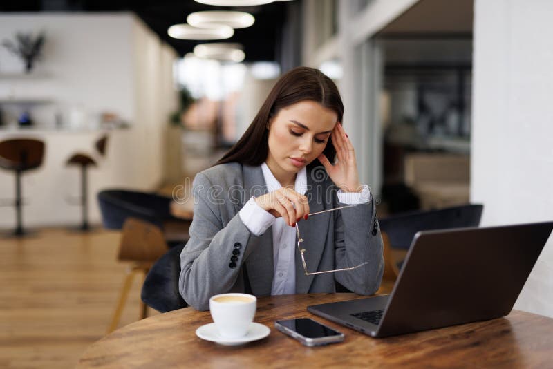 Joven y guapa emprendedora exhausta usando el portátil en una cafetería imágenes de archivo libres de regalías