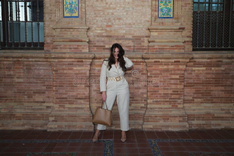Joven y hermosa mujer con el pelo castaño largo está en la plaza más famosa de seville. la mujer adopta posturas diferentes y fotografía de archivo