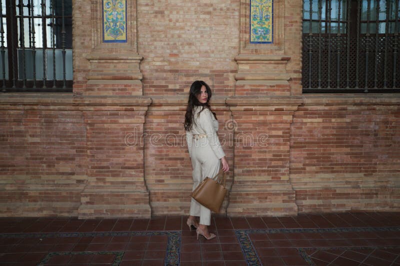 Joven y hermosa mujer con el pelo castaño largo está en la plaza más famosa de seville. la mujer adopta posturas diferentes y imagenes de archivo