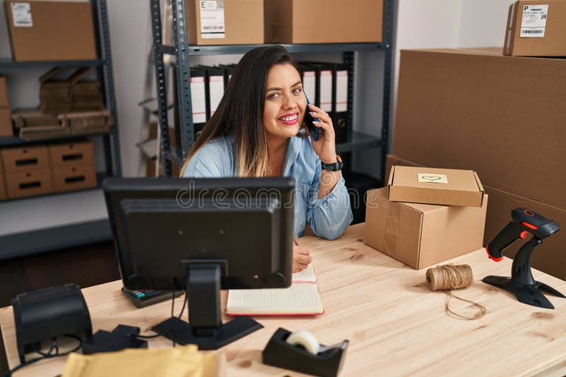 Joven y hermosa mujer de mayor tamaño que trabajadora de negocios de ecommerce hablando sobre escritura de smartphones en un orden fotografía de archivo libre de regalías