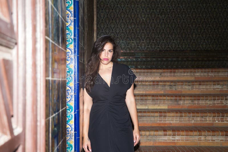 Joven y hermosa mujer de pelo largo marrón caminando por las escaleras de un monumento en seville la mujer tiene depresión y está fotos de archivo