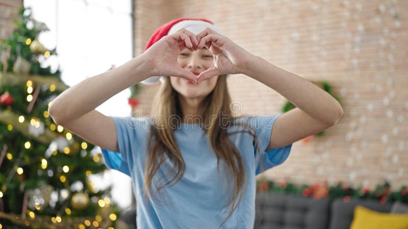 Joven y hermosa mujer hispana con forma de corazón con las manos celebrando navidades en casa fotografía de archivo