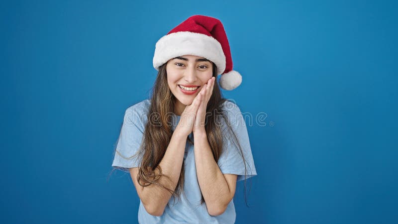 Joven y hermosa mujer hispana sonriendo confiada usando sombrero de navidad sobre aislado fondo azul fotos de archivo libres de regalías