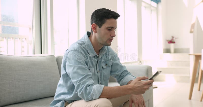 Joven y serio hispano navegando por las redes sociales por teléfono móvil almacen de metraje de vídeo