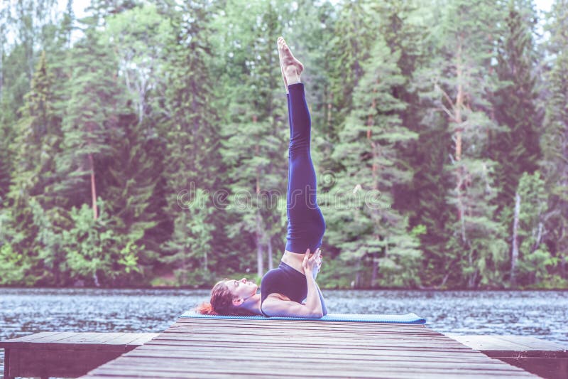 Joven yogi chica practicando yoga de pie en salamba sarvangasana ejercicio apoyado hombro soporte pose en el lago. concepto imágenes de archivo libres de regalías
