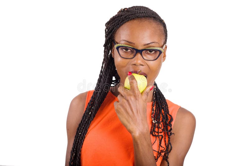 Jovencita con manzana. Joven de pie en un tanque de color naranja sobre fondo blanco comiendo manzana mirando la cámara