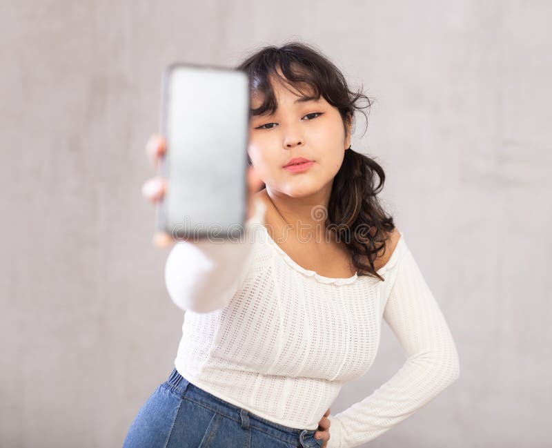 Jovencita disgustada sosteniendo un teléfono móvil