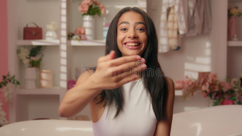 Jovencita Hispana amigable y sonriente, alegre mujer feliz en un baño rosa señalando a la cámara almacen de video