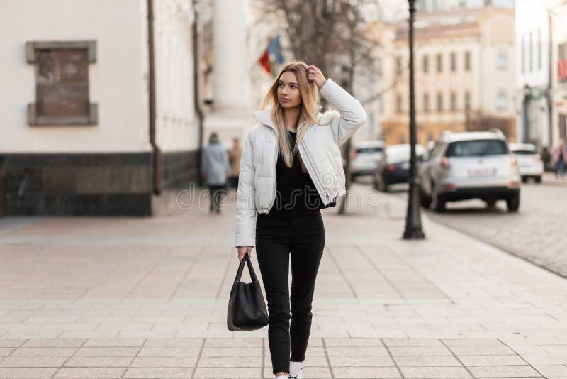 Jovencita Urbana Una Elegante Chaqueta Blanca En Vintage Negros Con Una Elegante Bolsa De Cuero Negro En La Calle. Foto de archivo - Imagen negro, vaqueros: 197033342