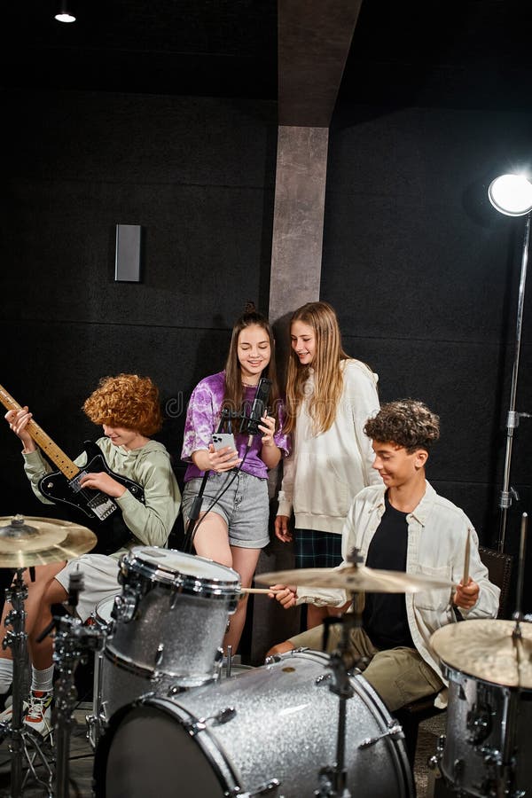 cheerful teenage girls singing while boys playing their drums and guitar in studio, musical group, stock photo. cheerful teenage girls singing while boys playing their drums and guitar in studio, musical group, stock photo