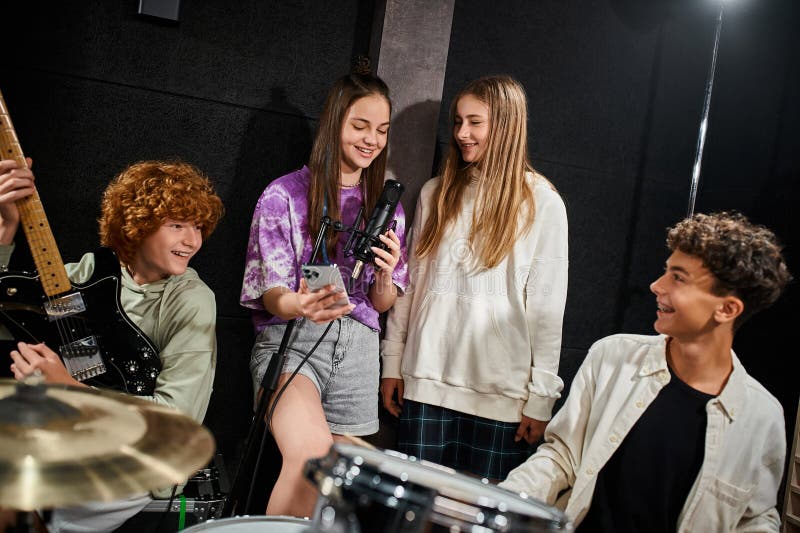 cheerful cute teenage girls singing and smiling while boys playing guitar and drums in studio, stock photo. cheerful cute teenage girls singing and smiling while boys playing guitar and drums in studio, stock photo