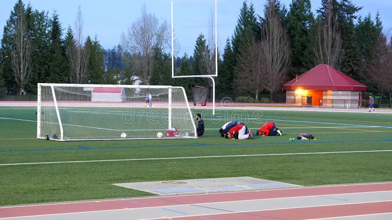 Jovens do Islã que rezam para seu deus antes do jogo de futebol