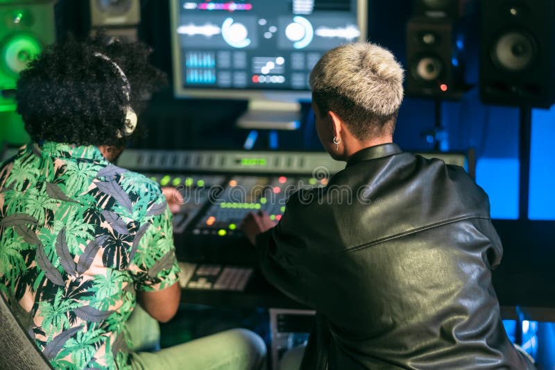Jovens engenheiros de áudio se divertindo trabalhando com controle de painel de som mixer dentro do estúdio de gravação de música