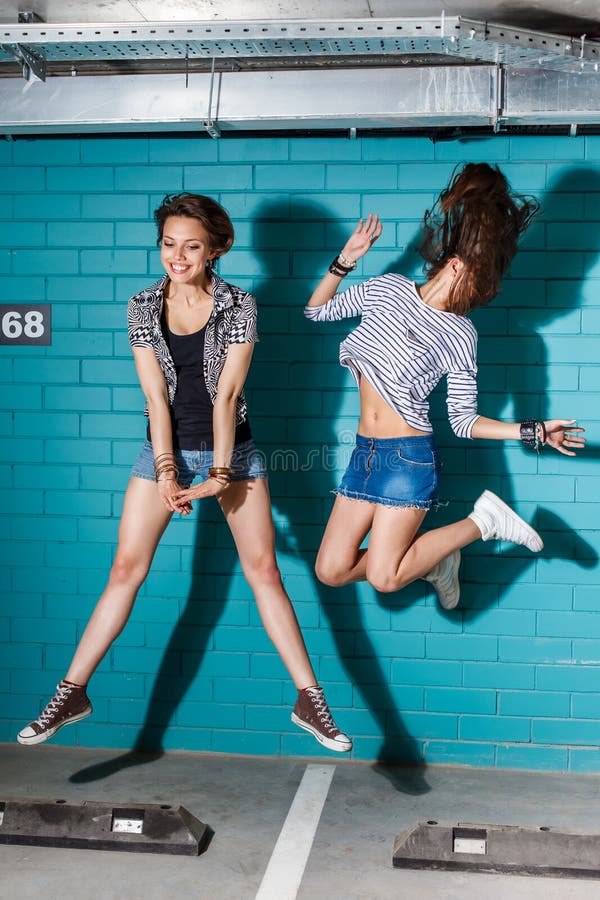 Jovens felizes que têm o divertimento e que saltam na frente do tijolo azul imagens de stock royalty free Jovens felizes que têm o divertimento e que saltam na frente do tijolo azul imagens de stock royalty free