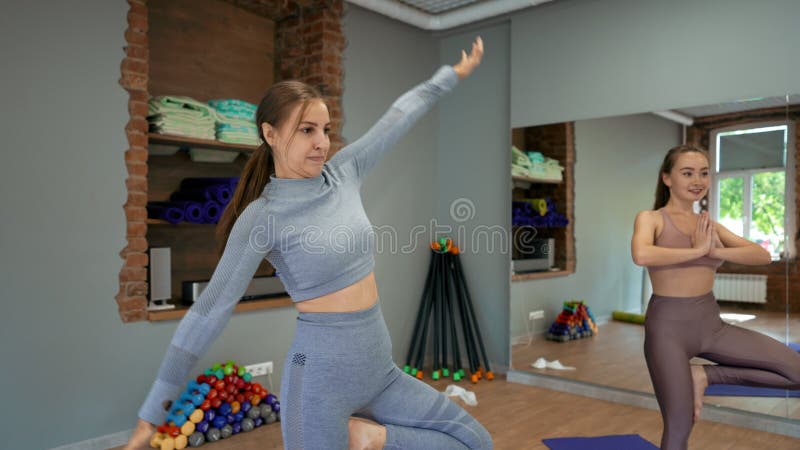 Jovens mulheres aprendem a fazer exercício de yoga em pose de árvore