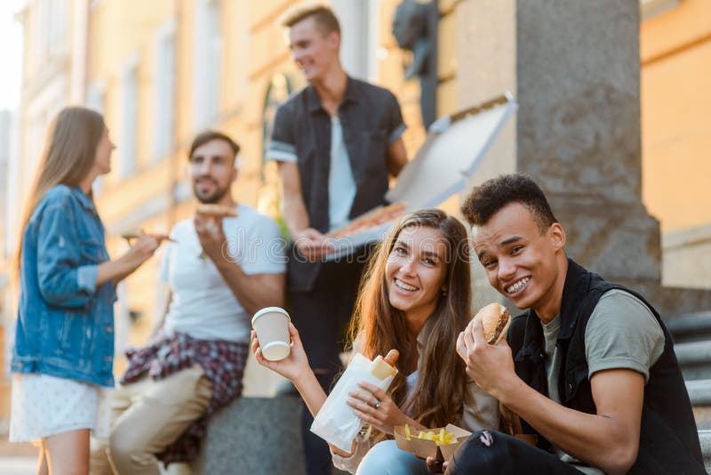 Jovens que comem o fast food imagens de stock Jovens que comem o fast food imagens de stock