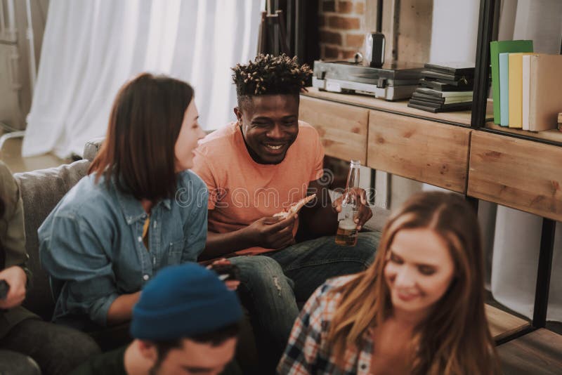 Jovens que conversam e que riem ao apreciar bebidas e alimento imagens de stock Jovens que conversam e que riem ao apreciar bebidas e alimento imagens de stock
