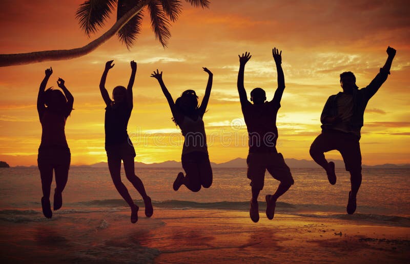 Jovens que saltam com excitamento na praia